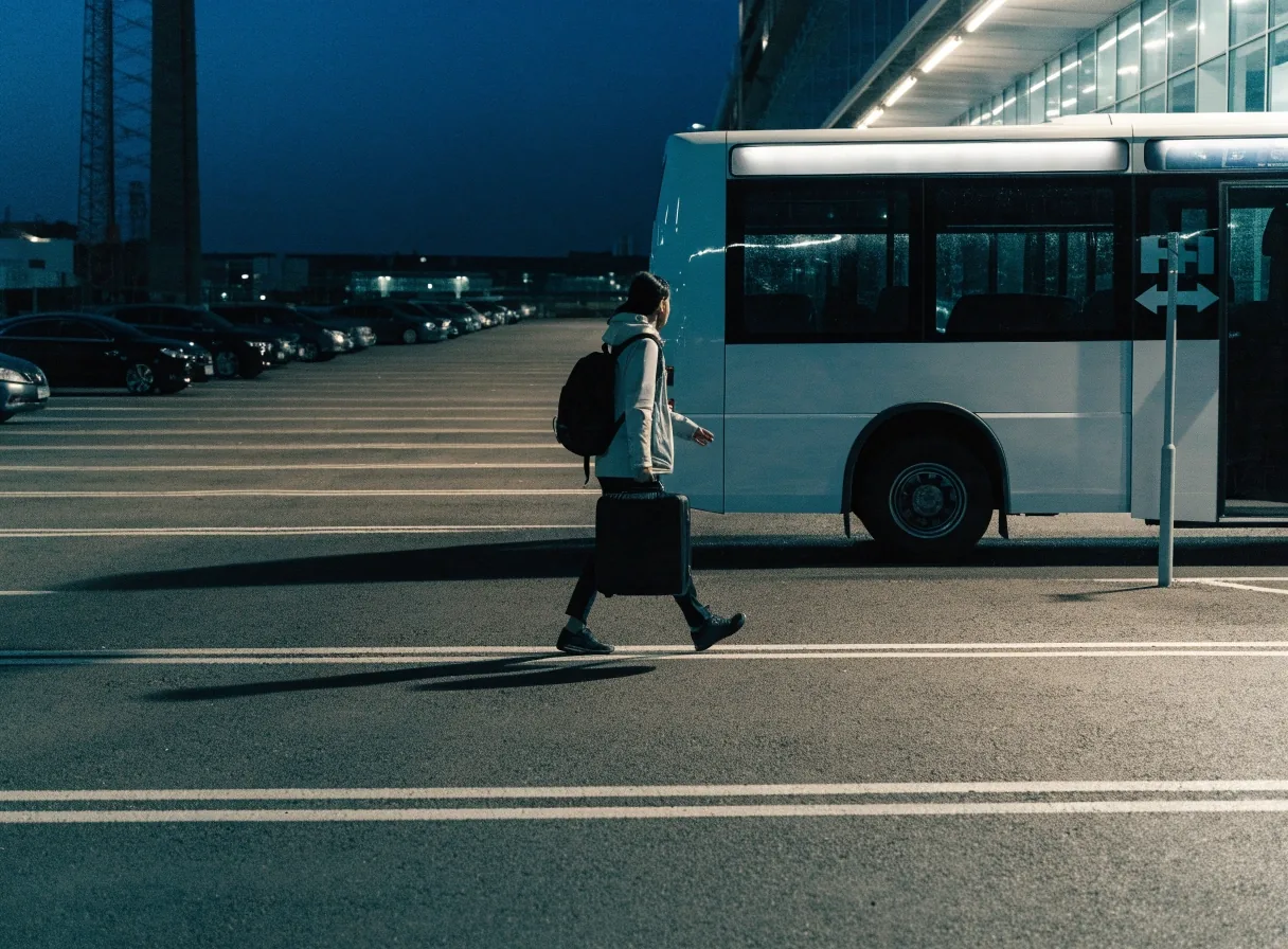 A shuttle bus idling in a quiet car park row near the Sydney Airport terminals at night
